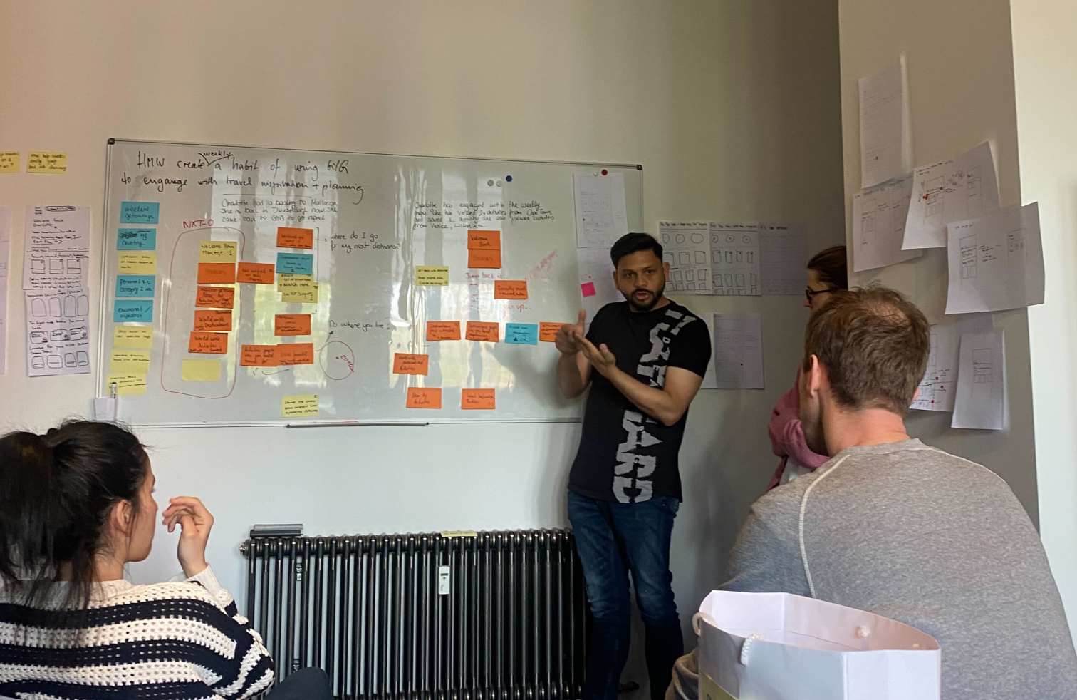 Workshop team gathered around a whiteboard mapping returning user journeys
